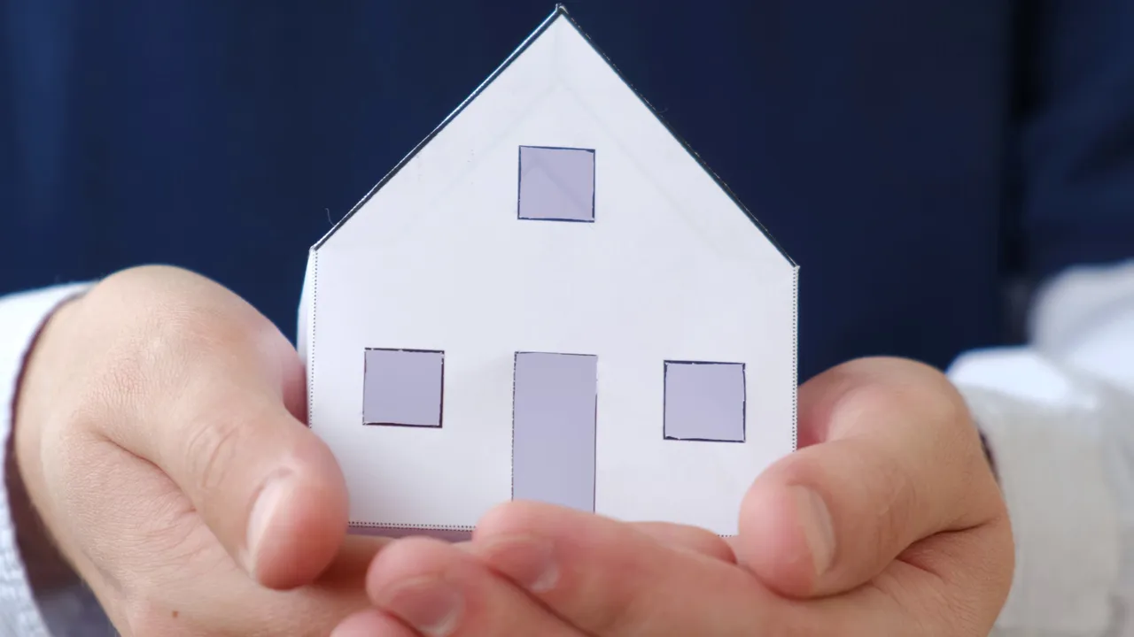 Hands holding paper house